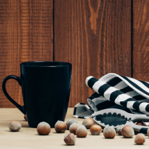 中焙-堅果散落在桌上、黑色咖啡杯、條紋布與木紋背板
